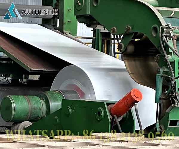 Proses pengolahan koil baja pada mesin pabrik modern untuk menghasilkan atap seng gelombang warna yang presisi dan berkualitas standar SNI.