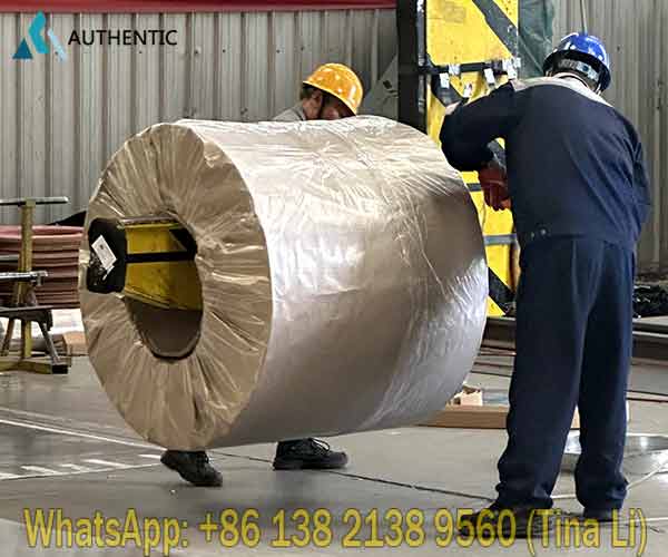 Experienced warehouse specialist applying heavy-duty waterproof protection during the manual packing process of printed PPGI steel coil at Authentic Steel factory.